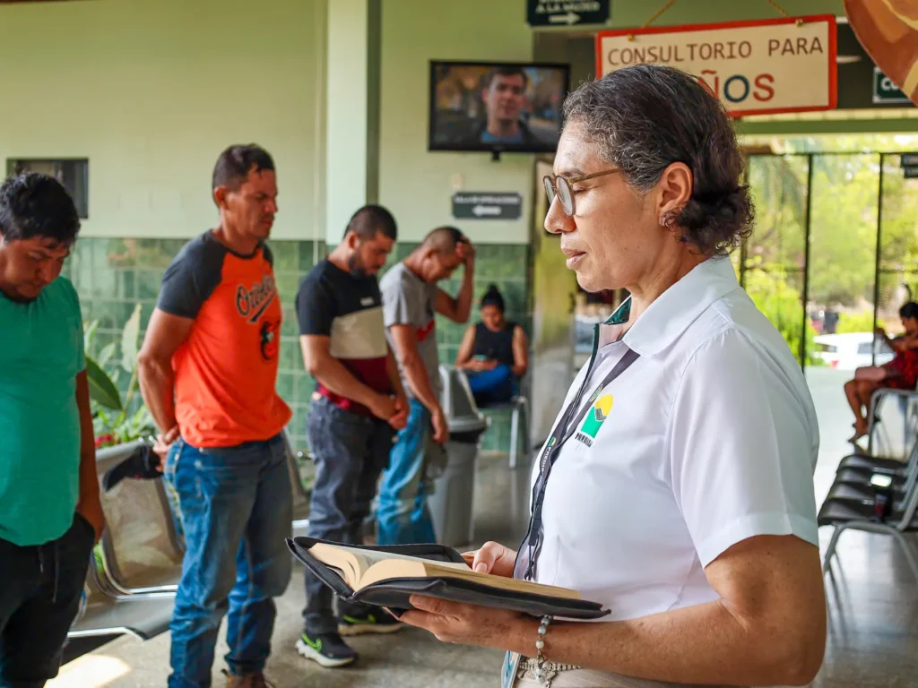 A chaplain at Predisan Christian Hospital prays with a group of men in the waiting area.
